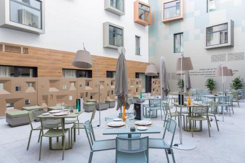 a restaurant with tables, chairs, tables, chairs and umbrellas at Hotel Macià Sevilla Kubb in Seville