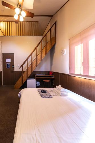 a room with a large white bed with a staircase at ETAVIA Yufuin Kinrinko in Yufuin