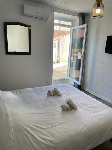 two slippers on a bed in a room with a window at Hôtel & Restaurant Le Patio VICHY in Vichy