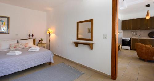 a bedroom with a bed and a mirror and a kitchen at 4Elies apartments in Vourvourou