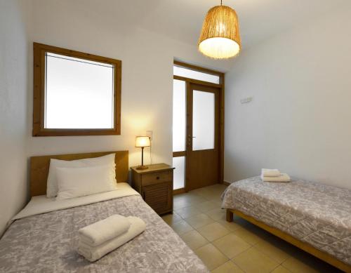 a bedroom with two beds and a lamp and a window at 4Elies apartments in Vourvourou