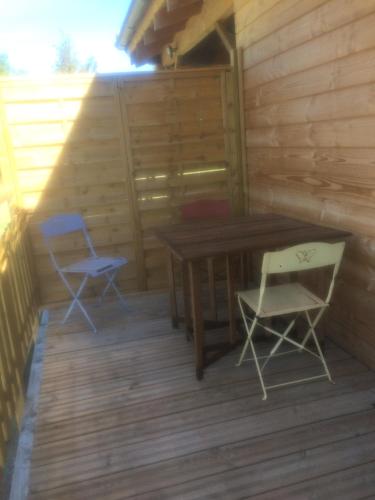 une terrasse en bois avec une table et deux chaises dans l'établissement L’Oiseau rêveur, à Darbres