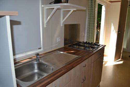 a kitchen with a sink and a stove at Camping maeva Escapades Le Casque Roi in Salavas