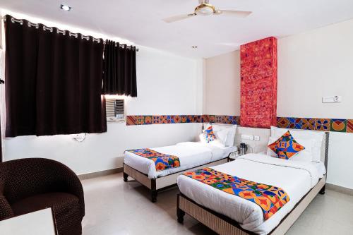 a hotel room with two beds and a chair at Hotel Omni Plaza in Jodhpur