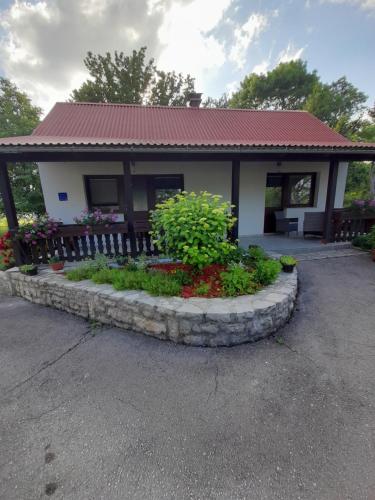 ein kleines Haus mit einem Zaun und ein paar Blumen in der Unterkunft Apartment Lena in Gornji Vaganac