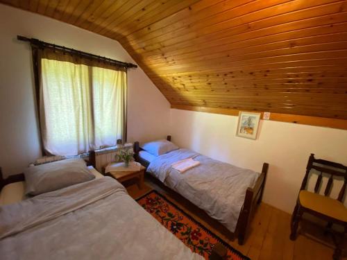 two beds in a room with a wooden ceiling at Mystic Forest Hostel in Mitrovac