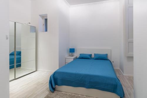 1 dormitorio con cama azul y espejo en Spacious Riverside Residency - Magnificent View en Budapest