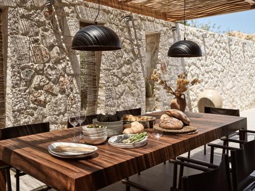 a wooden table with bread and wine glasses on it at Cielo villas - An Authentic Mediterranean Living in Zakynthos Town