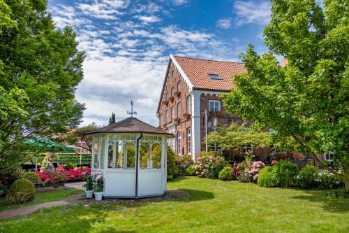 a gazebo in a garden in front of a building at Hotel Landhaus Steinfeld in Greetsiel