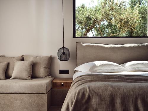 a bedroom with a bed and a couch and a window at Cielo villas - An Authentic Mediterranean Living in Zakynthos Town