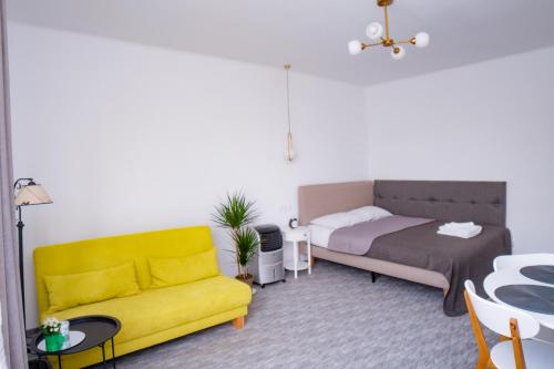 sala de estar con sofá amarillo y cama en Vladstudio, en Turda