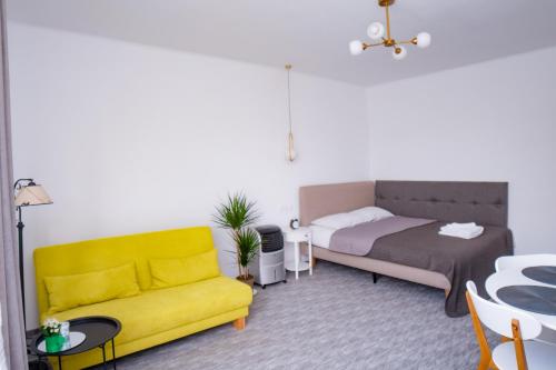 Una sala de estar con un sofá amarillo y una cama. en Vladstudio, en Turda