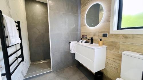 a bathroom with a white sink and a mirror at Ohope Villas with Spa,Sauna,Pool, Adults Only in Ohope Beach