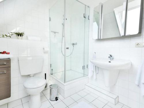 ein weißes Bad mit einer Dusche, einem WC und einem Waschbecken in der Unterkunft Ferienwohnung 39 Mauersegler - Urlaub in der Natur in Timmendorfer Strand