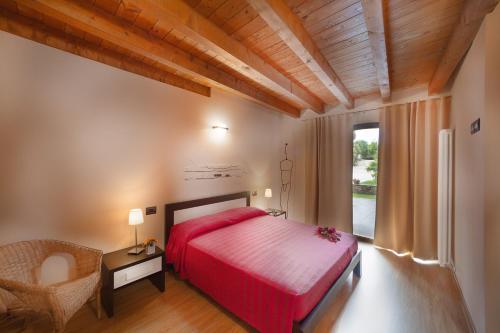 a bedroom with a red bed and a chair at La Casa del Nonno in Monzambano