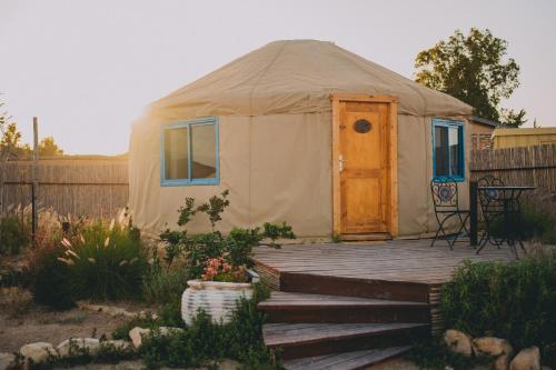 a yurt with a wooden deck in a yard at Alpaca Farm - חוות האלפקות in Mitzpe Ramon