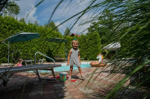 Ein kleiner Junge, der vor einem Schwimmbad steht. in der Unterkunft Villa Garden Hotel in Solotschyn