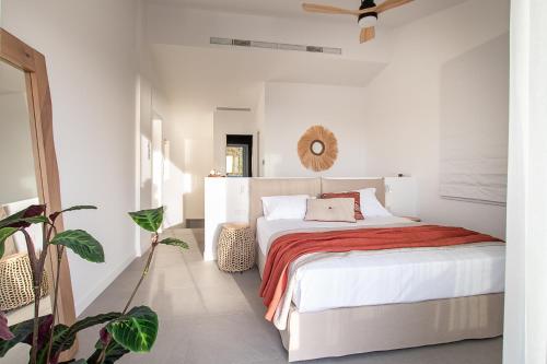 a white bedroom with a bed with a red blanket at LazySun in Sounio