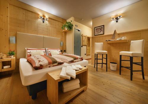 a bedroom with a bed and a table and two stools at Hotel Astra in Livigno