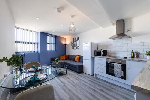 a kitchen and a living room with a table and a couch at Stunning 1 bed apartment in the heart of Stockport in Stockport