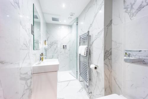 a white bathroom with a shower and a sink at No1 Apartments & Bedrooms St Andrews - St Mary's in St. Andrews