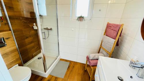 a bathroom with a shower and a toilet and a chair at Domki Agi in Jastrzębia Góra