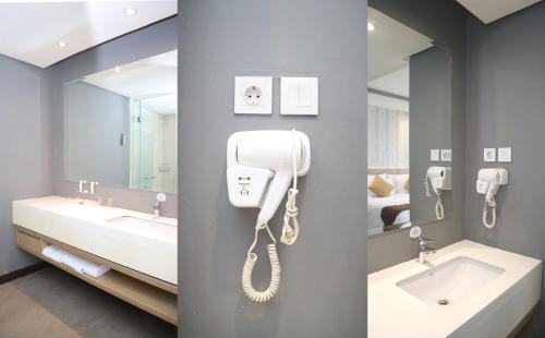 a bathroom with a phone on a wall next to a sink at Vasaka Hotel Jakarta Managed by Dafam in Jakarta