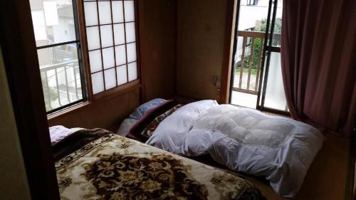 a small room with a bed and two windows at "Cherry House" is Direct to Narita,Haneda AP, Disney, Asakusa, Skytree Tower, Tokyo in Matsudo