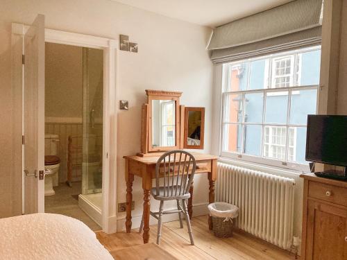 a bedroom with a desk and a chair and a window at The Little Rose in Lyme Regis
