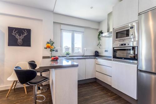 a kitchen with white cabinets and a table with chairs at San Jose 2 baños in Cádiz