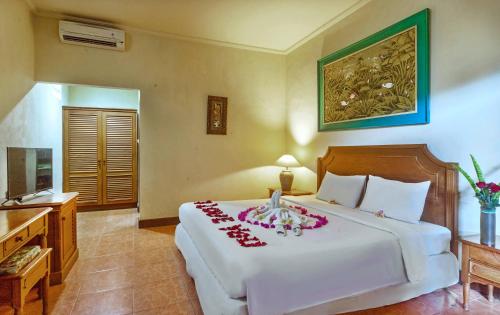 a bedroom with a large white bed with flowers on it at Dewi Sinta Hotel and Restaurant in Tanah Lot