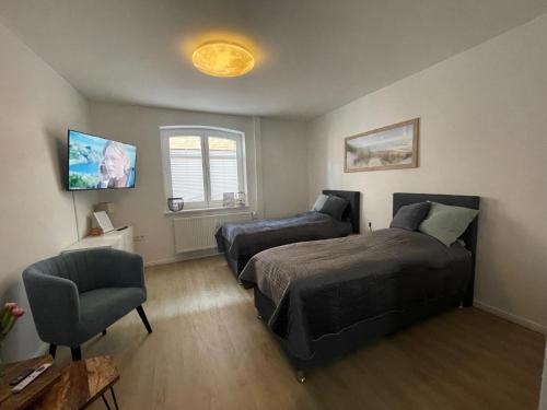 a bedroom with two beds and a chair at Fewo ToNi in Wismar