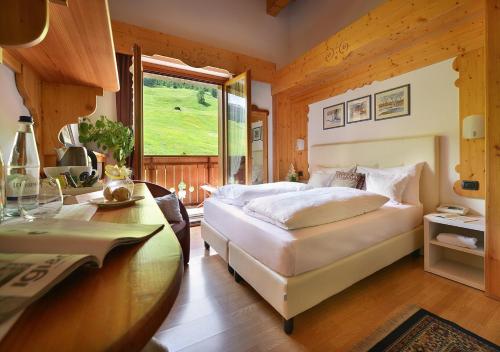 a bedroom with a bed and a desk and a window at Hotel Posta in Livigno