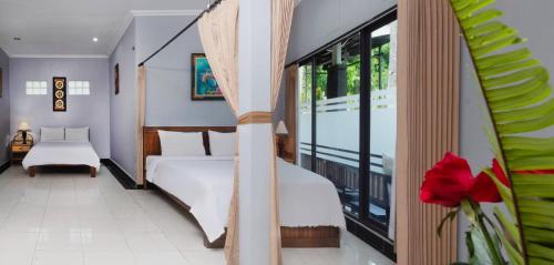 a bedroom with a bed and a large window at Dewi Sinta Hotel and Restaurant in Tanah Lot