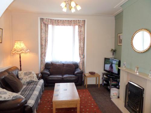 Una sala de estar con un sofá y un televisor. en Stay Llandudno, en Llandudno
