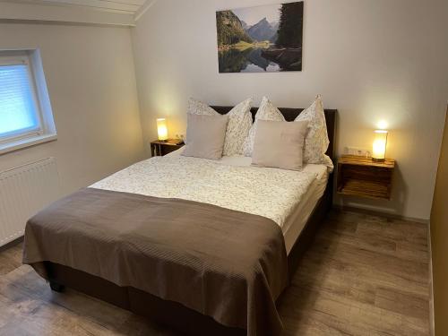 een slaapkamer met een bed met kussens en 2 lampen bij Ferienwohnung Andexlinger in Abtenau