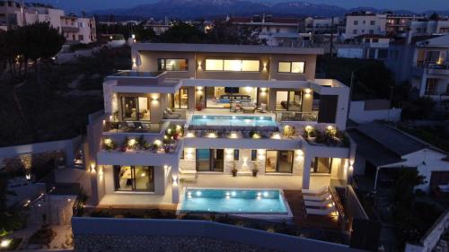 a large white house with a swimming pool at night at Seafront Villas I Luxury stay next to the sea in Chania Town