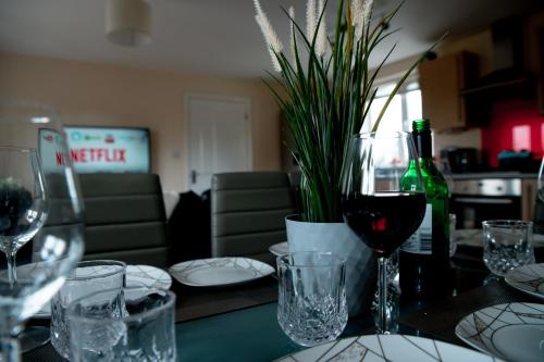 a table with wine glasses and a bottle of wine at Chichele House, sleeps 8, Nr Rushden Lakes, allocated parking, corporate welcome in Higham Ferrers