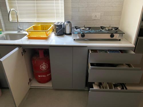 a kitchen counter with a stove and a sink at Palmo Holiday Apartments in Kathmandu