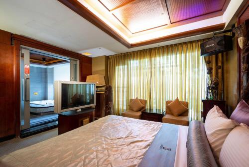 ein Hotelzimmer mit einem Bett und einem Fernseher in der Unterkunft In-stone Motel in Taipeh