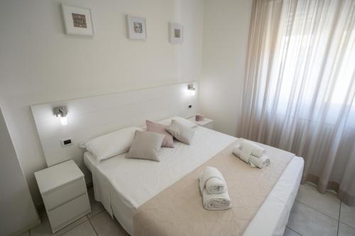 a white bedroom with a large white bed with pillows at Rimini Bay Suites&Residence in Rimini
