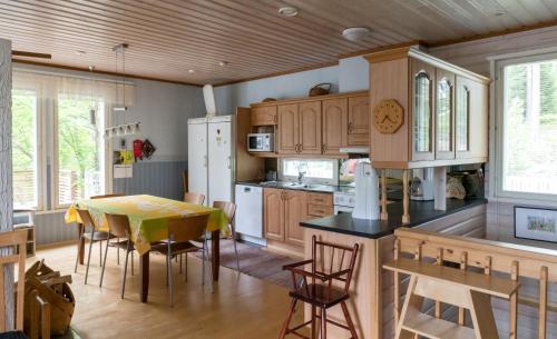 una cocina con armarios de madera, mesa y sillas en Talo Valoisa, en Rovaniemi