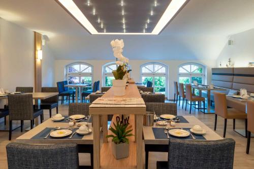 a dining room with tables and chairs in a restaurant at Hotel Landhaus Steinfeld in Greetsiel