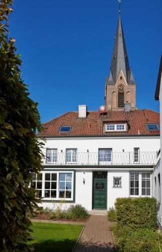 uma igreja com um campanário no topo de um edifício branco em Erler Koornhuus em Raesfeld