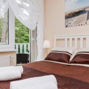 a bedroom with a bed with a book on it at Villa Puerto in Pobierowo