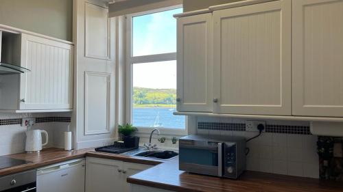 a kitchen with a microwave and a window at Beautiful Upper Apartment/Stunning Sea Views, Isle of Bute in Port Bannatyne