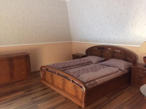a bedroom with a wooden bed and two night stands at Marcsi Ház in Balatonlelle