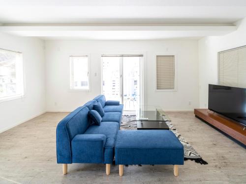 a living room with a blue couch and a tv at サンセットリゾート　かぬたん in Gushiken