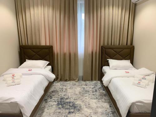 two twin beds in a room with curtains at Medion Apartments in Tashkent