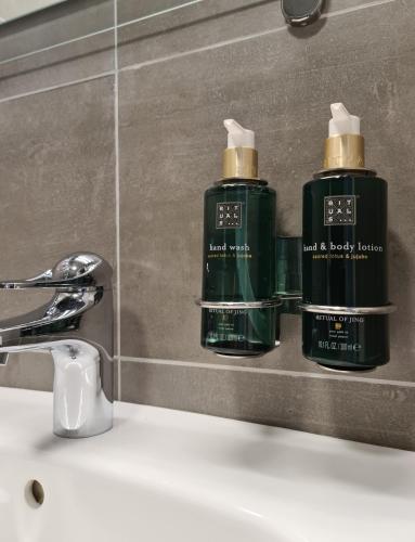 two green bottles ofodorizers sitting on a bathroom sink at Hemavans Wärdshus in Hemavan